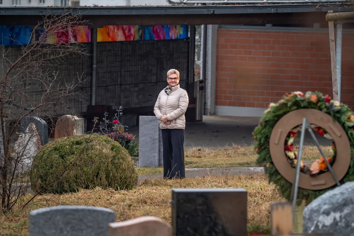 Dass sie manchmal auch Menschen auf ihrem letzten Gang begleitet, die sie persönlich gekannt hat, empfindet Karin Hosang als Ehre. Frau auf einem Friedhof mit Gräbern und Kränzen im Rücken
